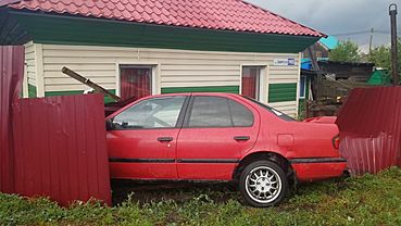 Красный автомобиль проломил забор жилого дома в Бийске